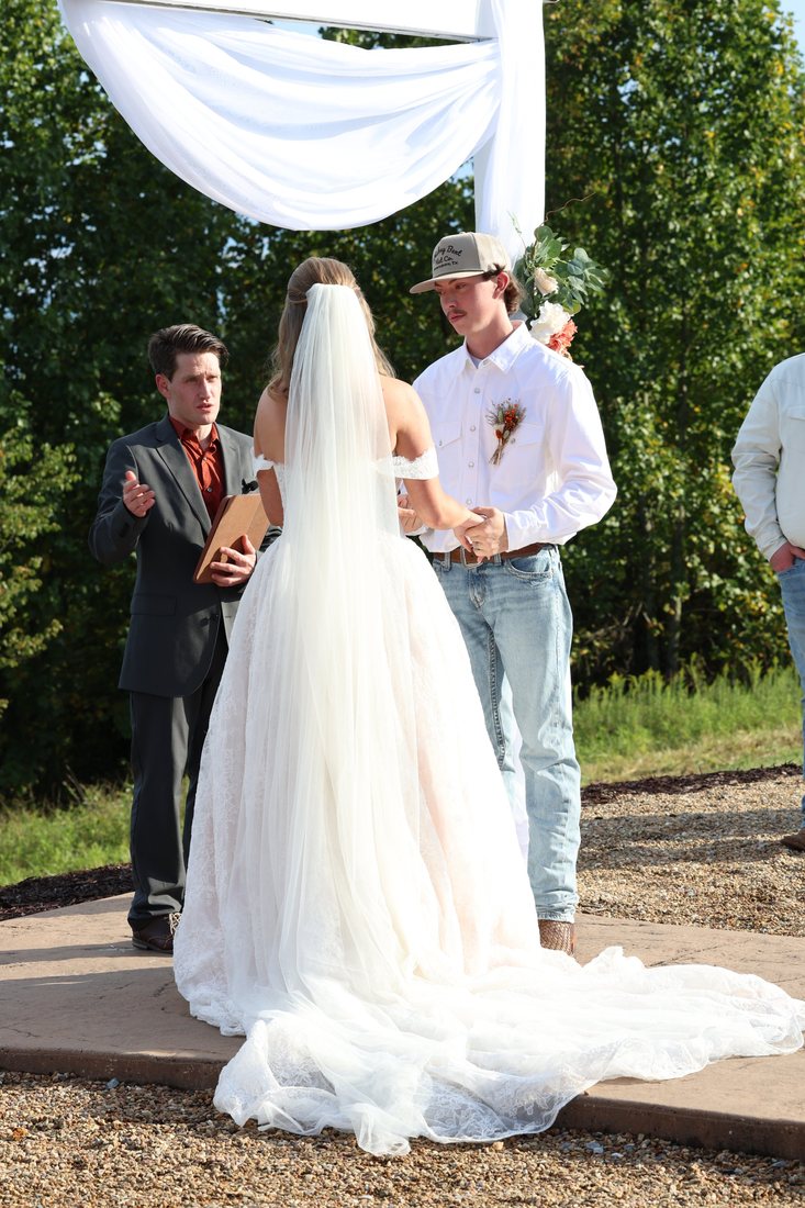 Nathan officiating as Autumn and Matthew hold hands under the draped arch