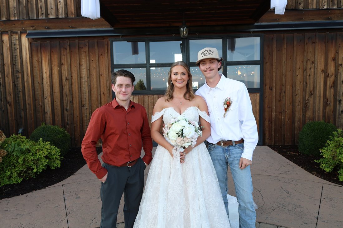 Autumn and Matthew with their officiant in front of the barn at Homeplace at Johnston Farms