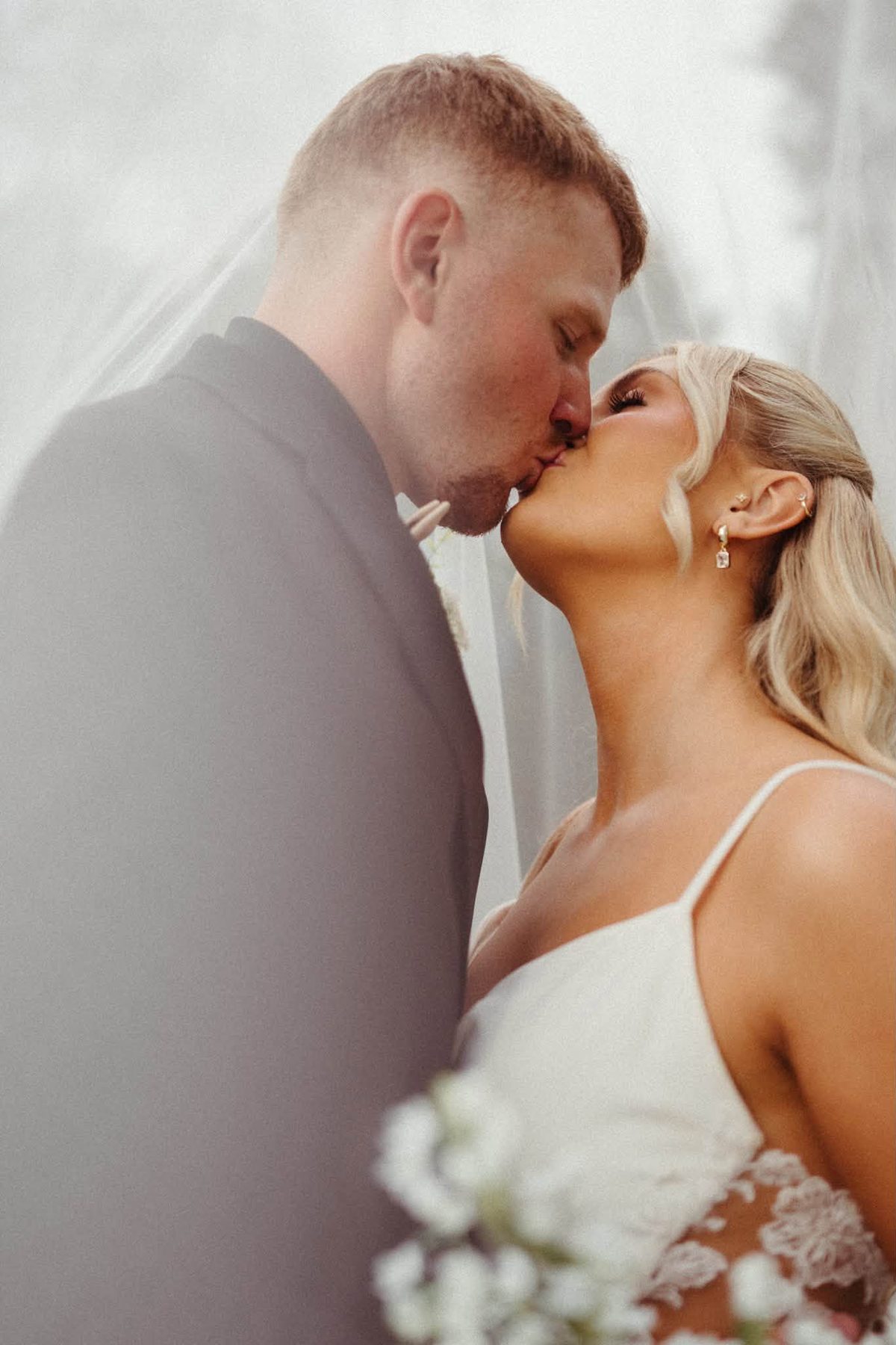 Cushi and Sam kissing beneath the veil